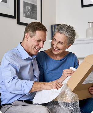 A smiling couple unpacks a package together at home.