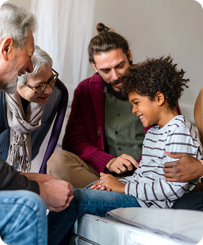 A smiling family gathers warmly around a happy child.
