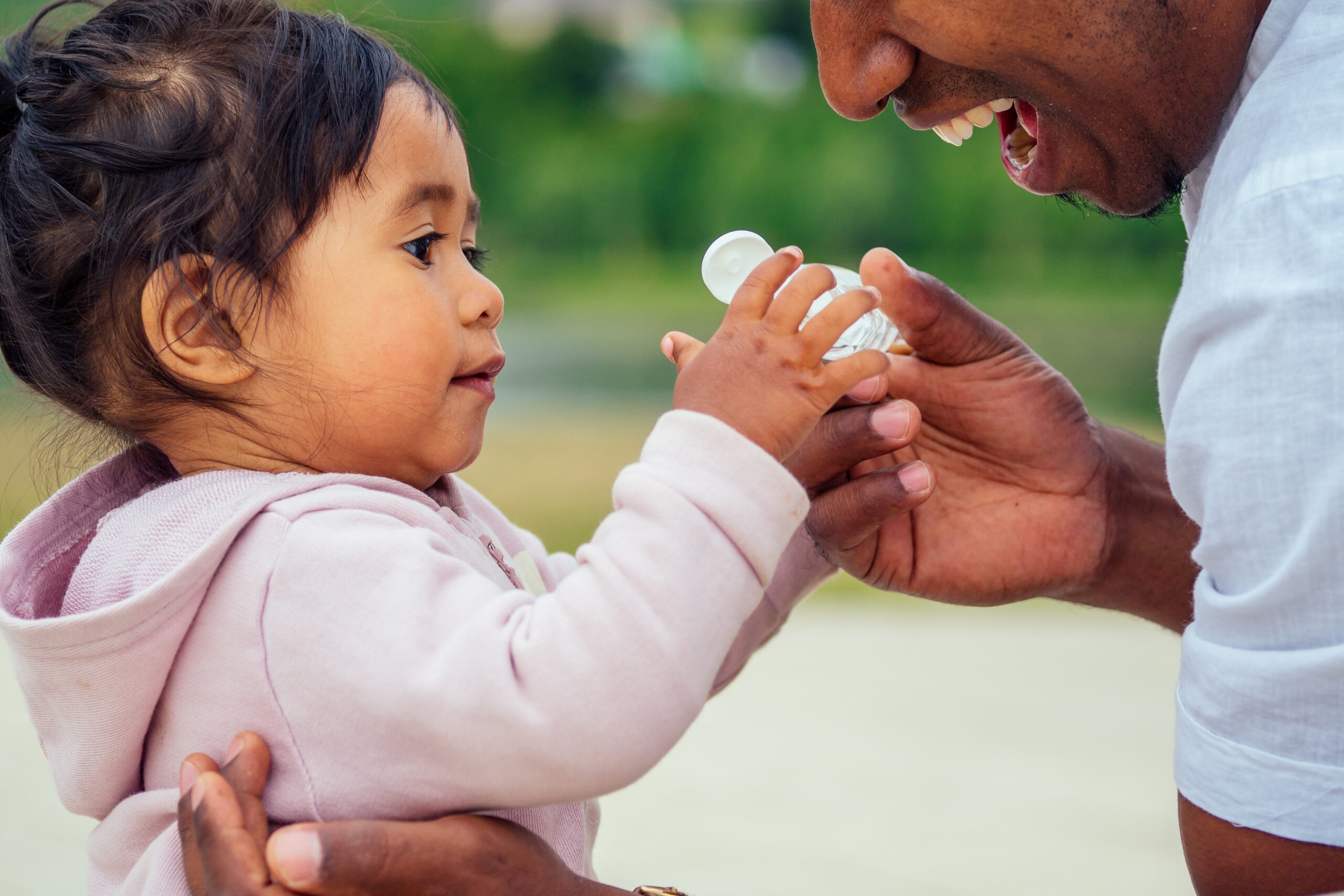 happy family applying hand-sanitizer anti-bacterial gel to daughter hands.