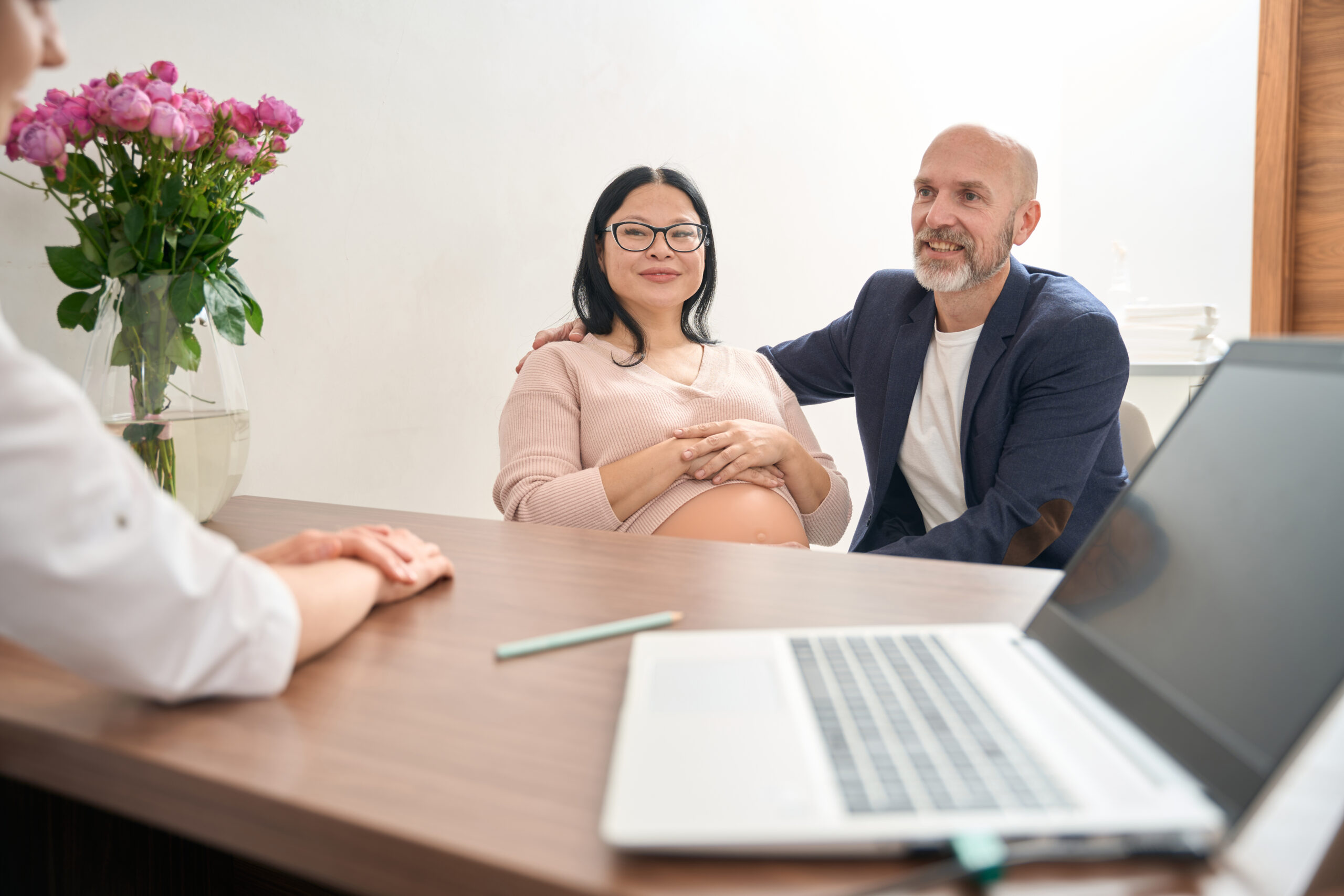 Adult husband and his pregnant wife visiting gynecologist office for routine health check-up of baby, second trimester examination, private consultation